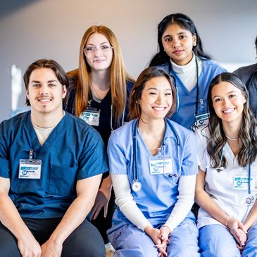 A group of diverse healthcare students smiling together in scrubs.