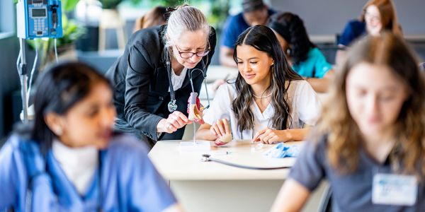 Teacher explaining anatomy to nursing students in a classroom.