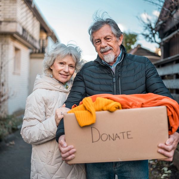 Elderly couple holding a donation box outside.