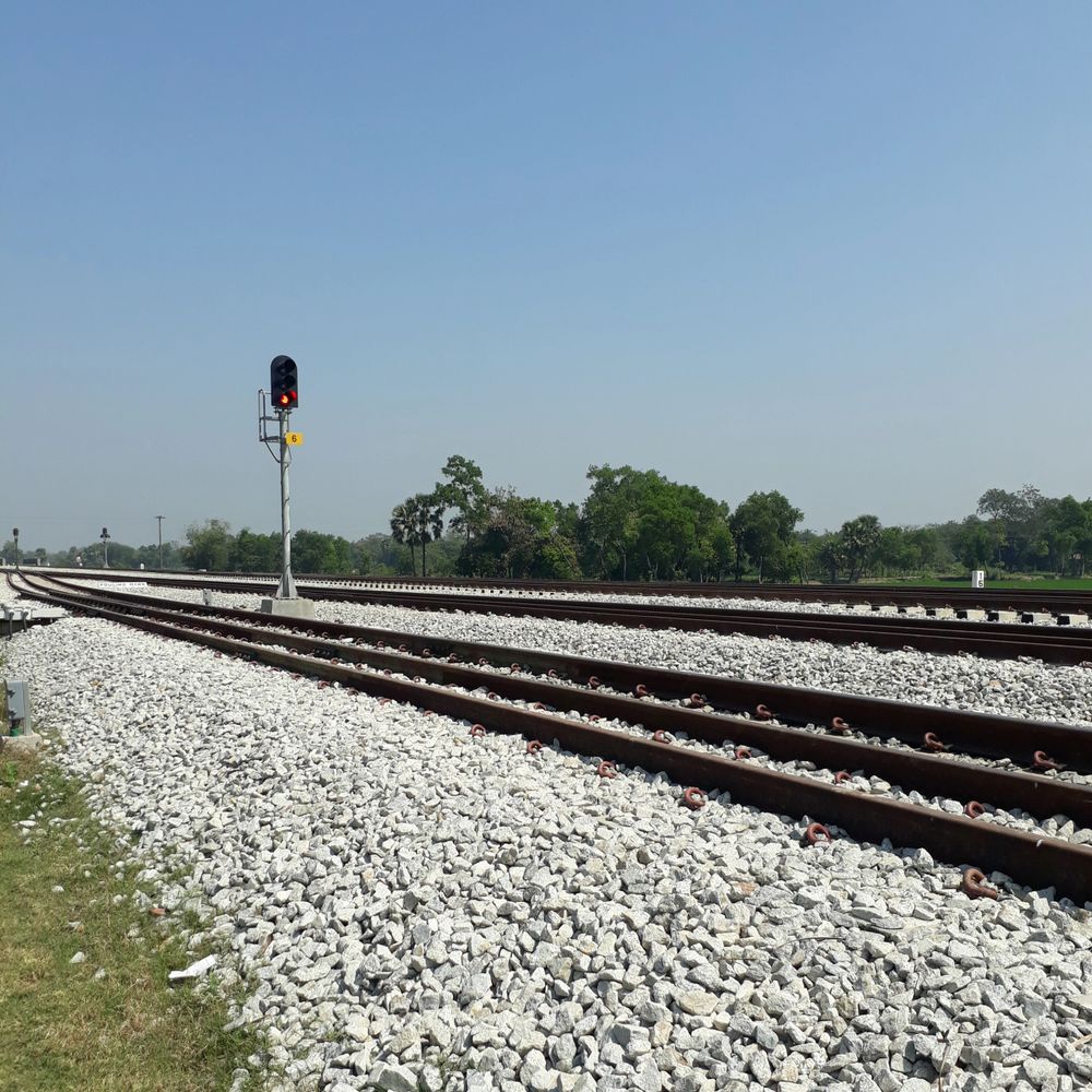 Railway tracks with a red signal light on a clear day.