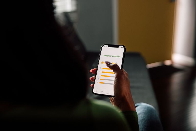 Close up on customer man hand pressing on smartphone screen with five star rating feedback icon and press level good rank for giving best score point to review the service