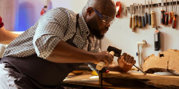 A craftsman chiseling wood with precision in a workshop.