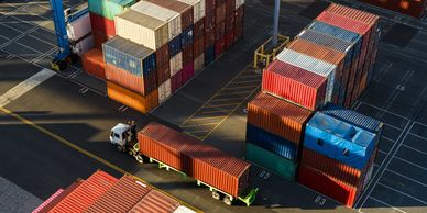Aerial view of stacked shipping containers and a truck in a busy port.