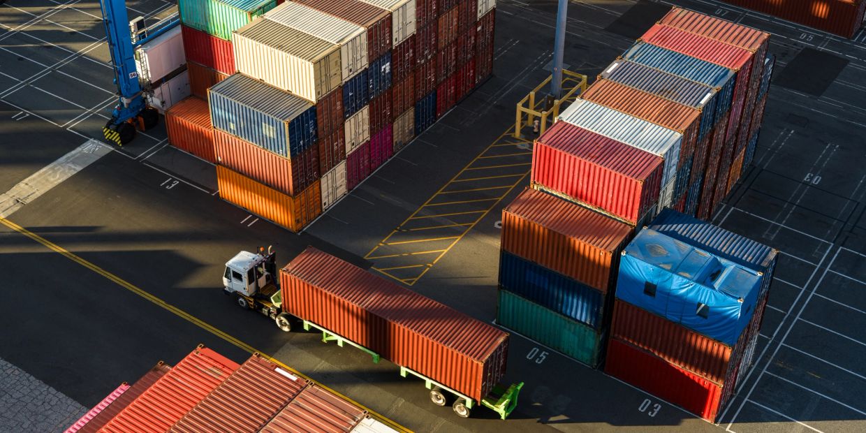 Shipping containers and a truck at a busy port during sunset.