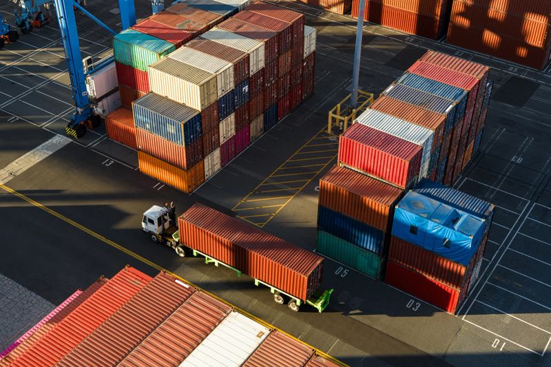 Drone shot of a terminal tractor driving between shipping containers in a massive intermodal container yard in the Port of Long Beach at sunset. 

Authorization was obtained from the Port of Long Beach Security Division and POLB Harbor Patrol for this operation in restricted airspace.
