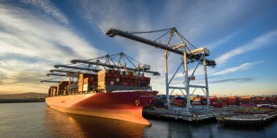 Container ship docked at port at sunset.
