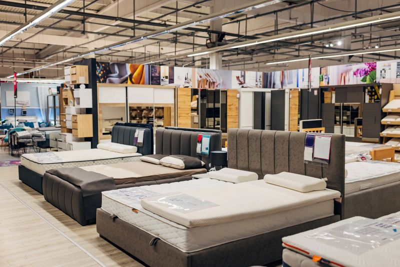 Beds and mattresses lined up next to each other are displayed in a department store