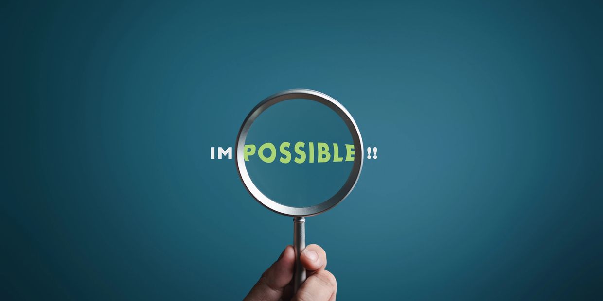 The word impossible with a magnifying glass over just the word possible