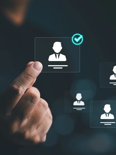Hand selecting a digital profile with a checkmark among multiple profiles.