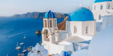 Santorini'nin mavi kubbeli kiliseleri ve Ege denizi manzarası.