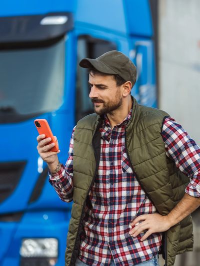 young man outside a semi truck looking at his phone