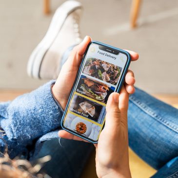 Person browsing food delivery options on a smartphone app while relaxing.