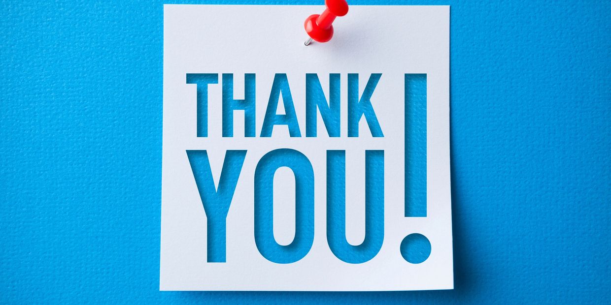 White paper with "THANK YOU!" cut out, pinned on blue background.