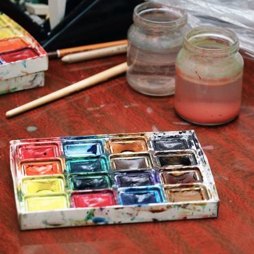 Watercolor palette and brushes on a wooden table.