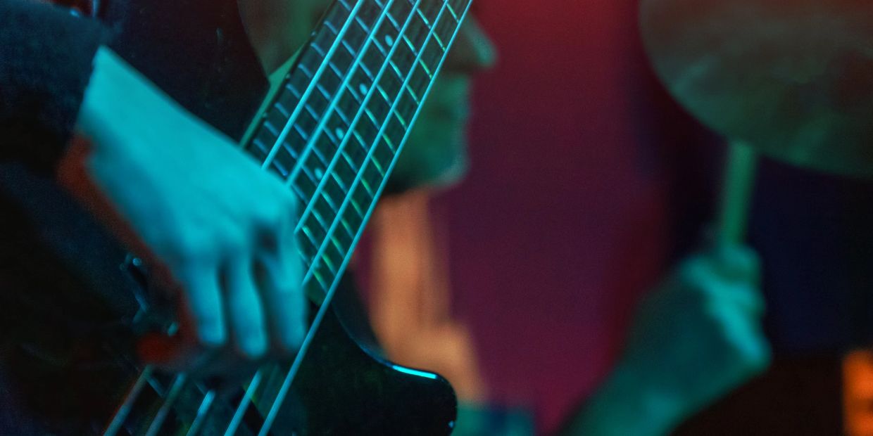 Close-up of a musician playing an electric guitar in blue lighting.