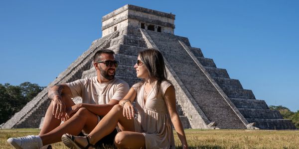 Couple sitting near ancient pyramid on a sunny day.