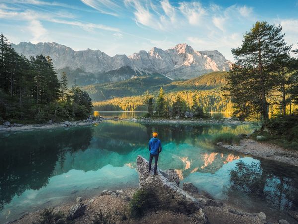 A human exploring a lake with mountains and trees in the background