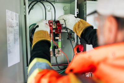 Electrician working on a circuit breaker inside an electrical panel.