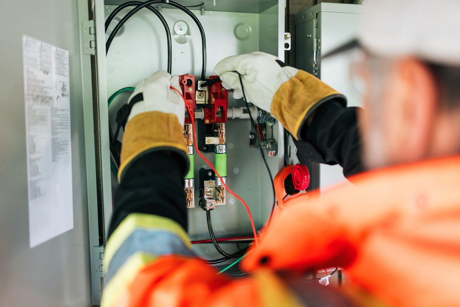 A professional solar panel crew installs a solar panel system on a house in Washington state, USA.  Green environmentally friendly energy.  The electrician checks the photovoltaic junction box  to make sure everything is working correctly.