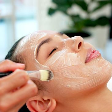 Woman getting a facial mask applied with a brush.
