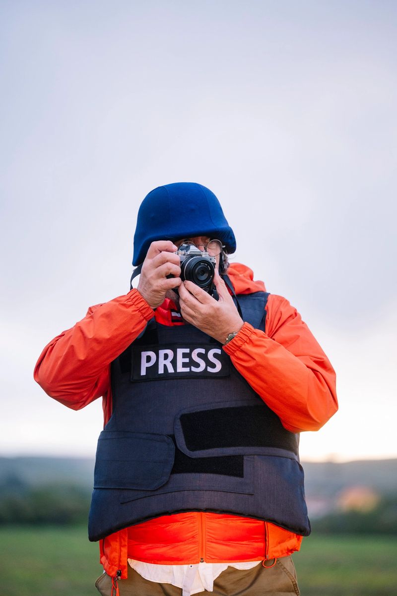 Reporter in bulletproof vest holding a camera.
