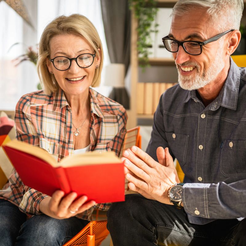 mature senior couple man and woman husband and wife read book at home