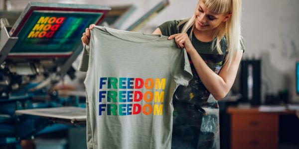 Woman holding a colorful freedom t-shirt.