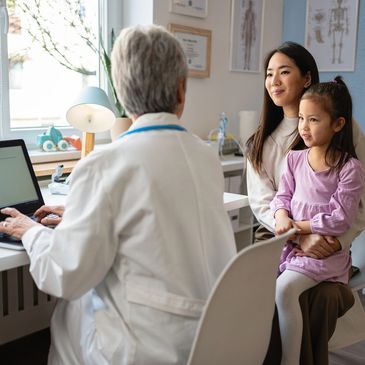 Mother and daughter consulting with a doctor in a clinic.