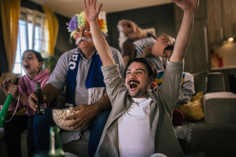 multigeneration family celebrating  success of their sports team while watching a game on tv  at home