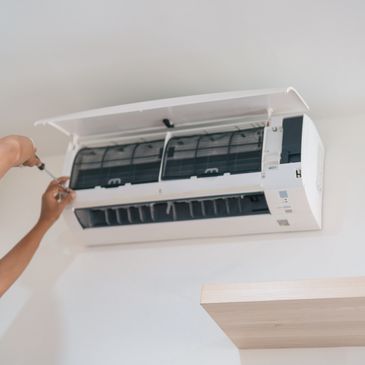Person repairing air conditioner on wall.