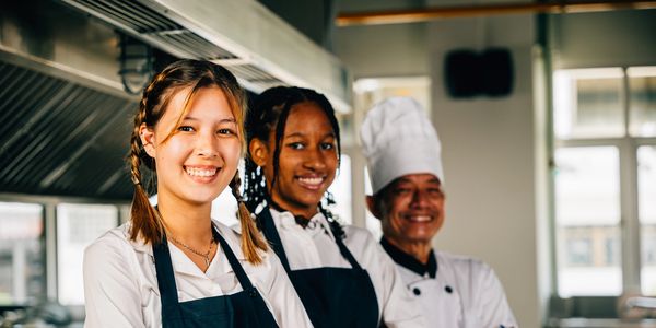Three chefs smiling in a kitchen.