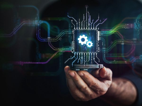 Hand holding a digital microchip with glowing gears and circuit connections.