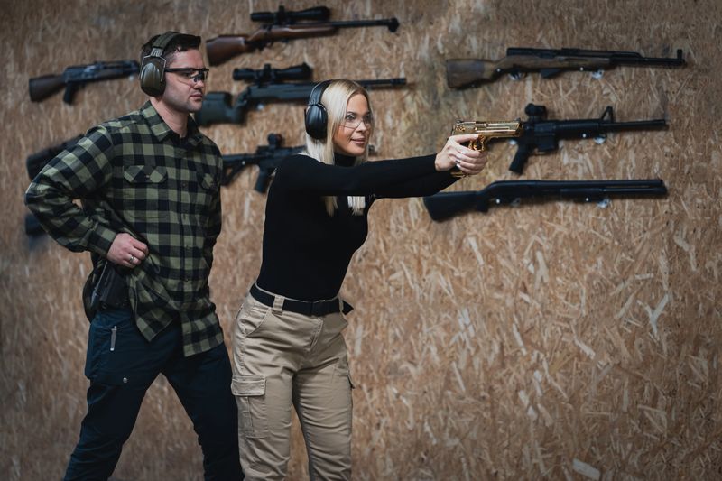 A young girl is training to shoot a pistol with an instructor at a shooting range. High quality photo