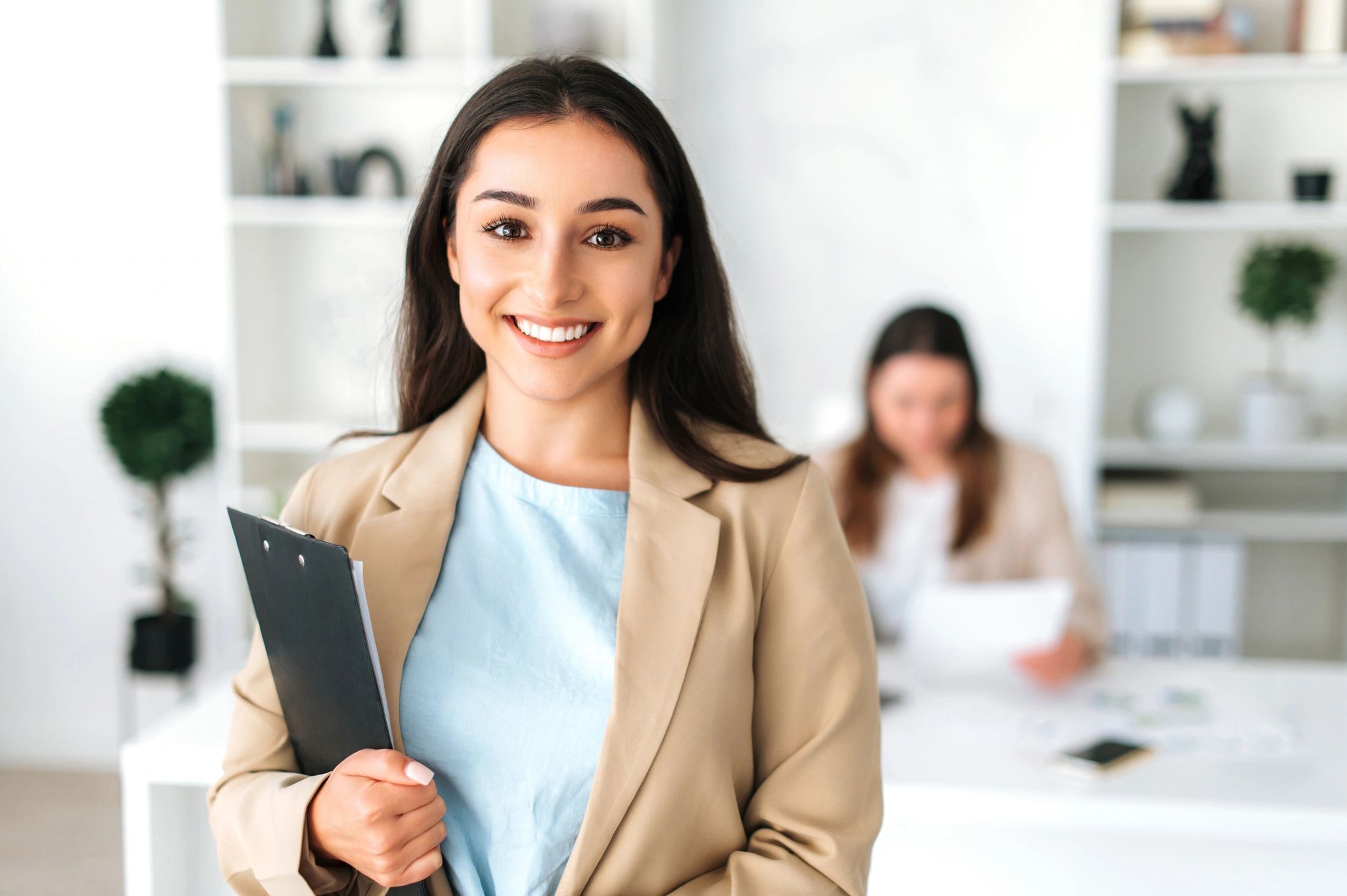 Confident businesswoman holding a clipboard and smiling at the camera.