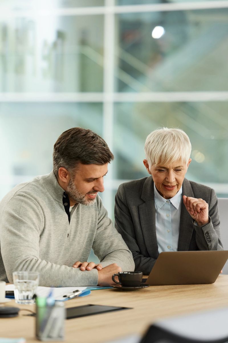 Happy male customer and his financial advisor working on a computer during a meeting in the office.