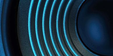 Close-up of a speaker cone with blue lighting highlighting its ridges.