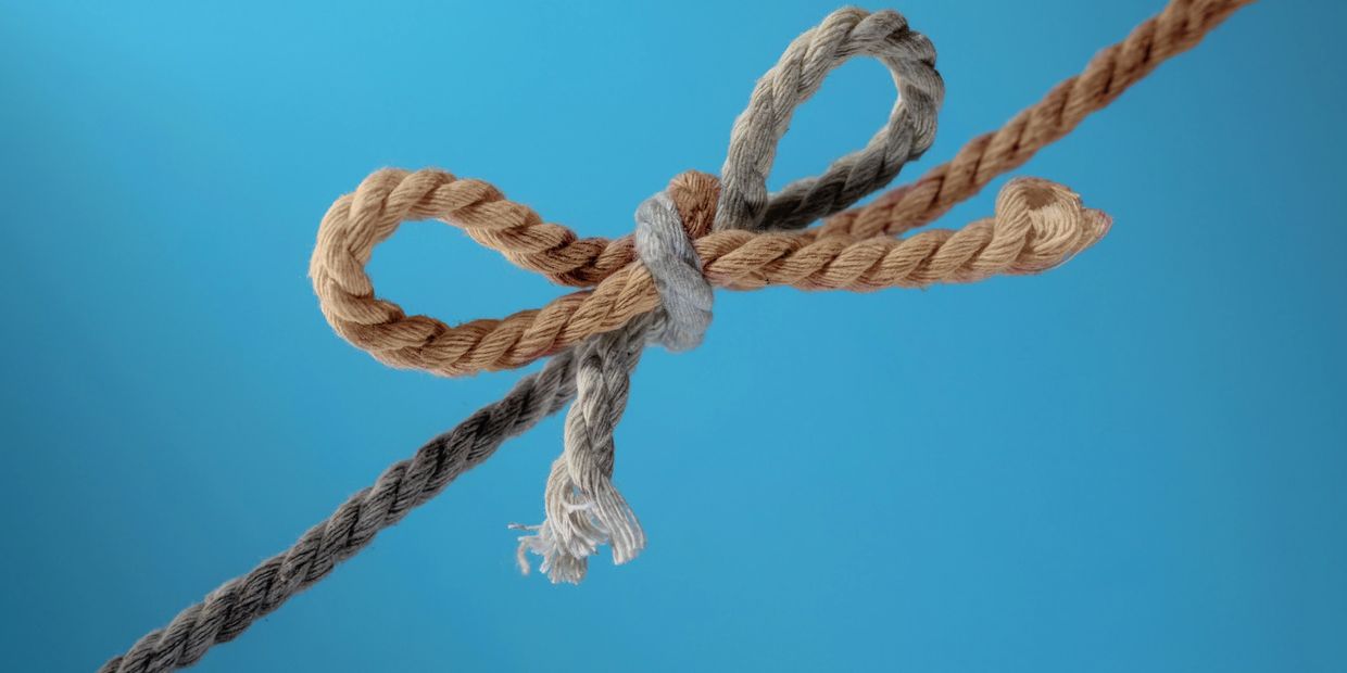 Two ropes tied together in a knot against a blue background.
