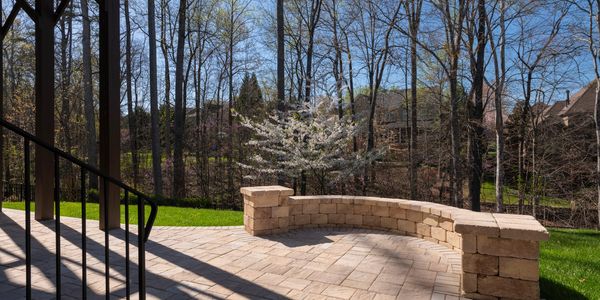 A backyard patio with a curved stone wall 