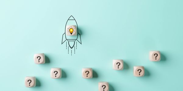 Wooden blocks with question marks and one with a lightbulb rocket illustration.