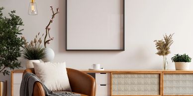 Cozy modern living room corner with leather chair, wooden sideboard, and plants.
