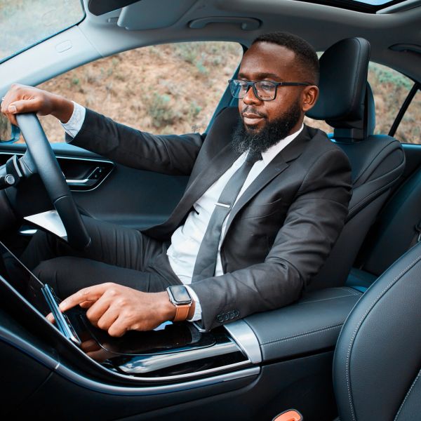 Man in a suit using the car's touchscreen controls while sitting in the driver's seat.