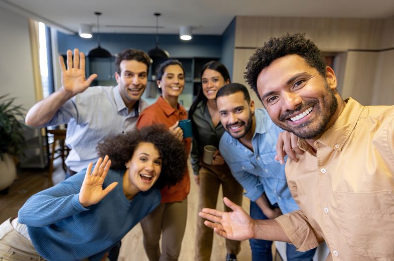 Happy group of Latin American coworkers taking a selfie in a coworking office and smiling