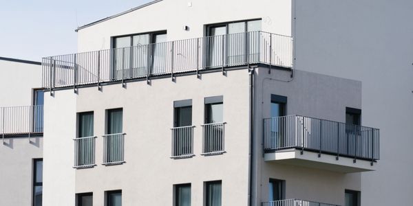 Modern white apartment building with balconies and large windows.