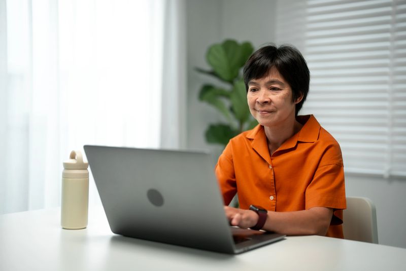 Asian mature woman working on laptop at home.