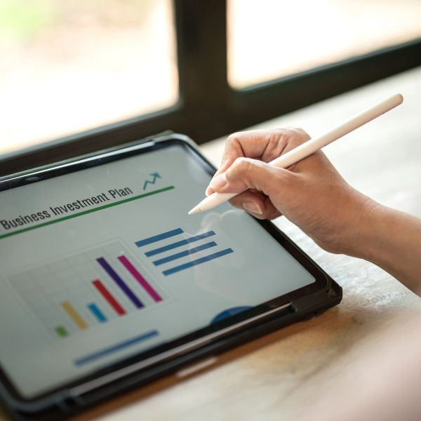 Person using a stylus to work on a business investment plan on a tablet.