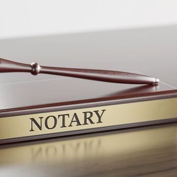 A wooden notary nameplate and gavel on a desk.