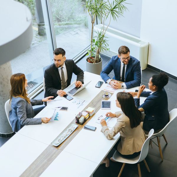 Five professionals in a business meeting around a modern table.