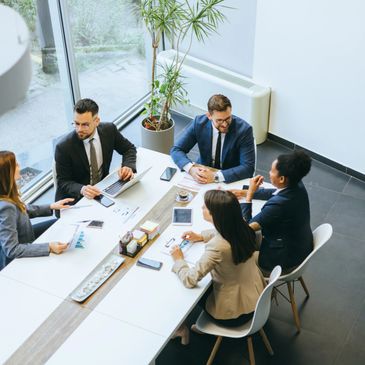 Business team discussing documents around a conference table in an office.
