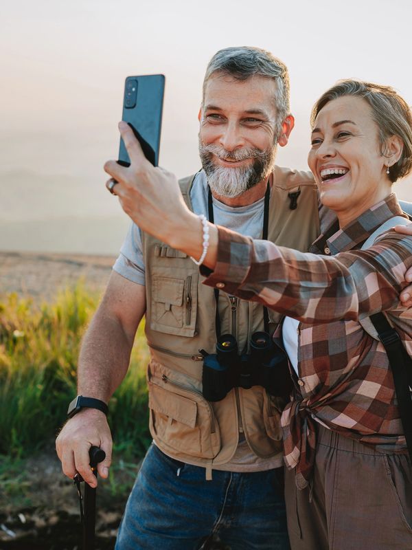 A old couple Travelling on the mountain and taking a selfie with camera