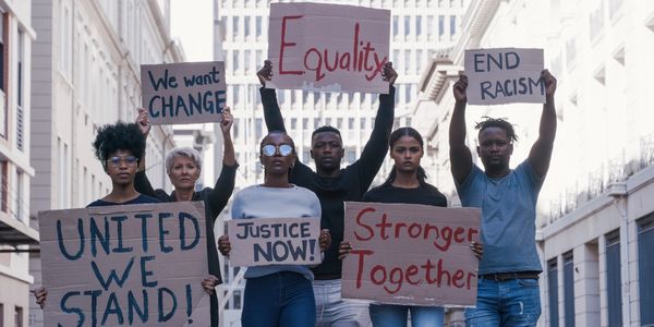 Group of various Americans of different ethnic groups protesting. They are hold signs that read: Uni